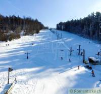 A snowy slope with a ski lift surrounded by forests in Stará Myjava.