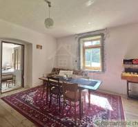 Dining room in a family house with a wooden table and a carpet, rustic furnishings.