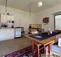 A kitchen in a family house with a wooden table, kitchen unit, and a tiled stove.