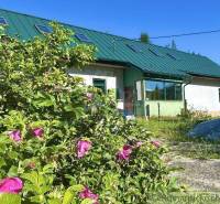 A family house in Spišská Nová Ves with greenery and pink flowers in the garden.