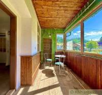A glazed veranda in a family house with wooden chairs and a view of the garden.