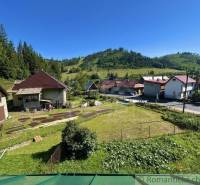 A family house in Spišská Nová Ves surrounded by green hills and a meadow plot.