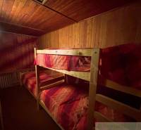 Bunk beds with red bedding in a wooden room of a family house.