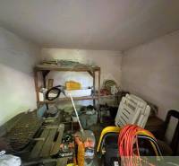 Storage space in a family house with a shelf, grill, and garden tools.