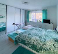 Bedroom in a family house with a large bed and green curtains, bright interior.