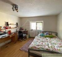 A bedroom in a family house with a bed, a desk, and simple lighting.