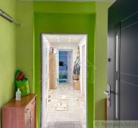 Hallway in a family house with colorful walls and a view into another room.