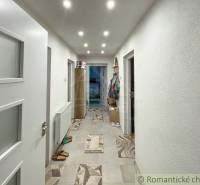 A hallway in a family house with lighting and tiled flooring.