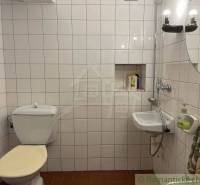 Bathroom with a toilet, sink, lights, and white tiles, peculiar property.