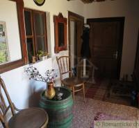 An entrance hall decorated with traditional chairs, a barrel, and floral decorations, a peculiar property.