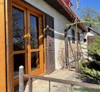 The exterior of the cottage with old wooden doors and greenery, ideal for unique properties.