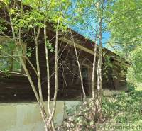 A wooden cottage in Liptovský Mikuláš surrounded by trees and greenery.