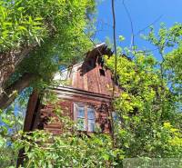 A cottage in Liptovský Mikuláš surrounded by dense greenery under a clear blue sky.