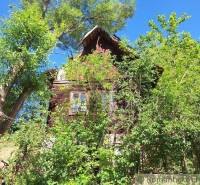 A wooden cottage in Liptovský Mikuláš surrounded by lush greenery and trees.