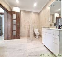 A bathroom in a family house with a sink, toilet, and wooden door.