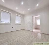 Empty room in a family house with glossy tiles and two windows.