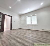 A family house with laminate flooring, white walls, and a window with internal blinds.