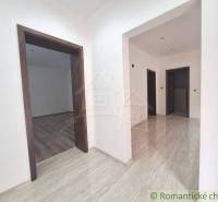 Interior of a family house with floating and light tiles, white walls, wooden frames.