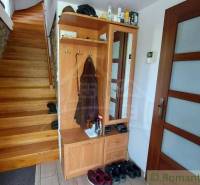 Interior of a family house with a wooden staircase, wardrobe, and stone wall.