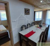 A dining room with a wooden ceiling, a set table, and an open passage to the bedroom in a family house.
