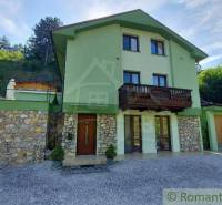 A family house in Dobrá Voda with stone details and a wooden balcony in a natural setting.