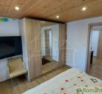 Bedroom with a wooden ceiling, bed, and cabinets in a family house.