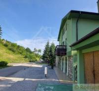 A family house in Dobrá Voda with a road, surrounding nature, and a green facade.
