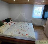 A bedroom in a family house with a cozy bed and a wooden ceiling.