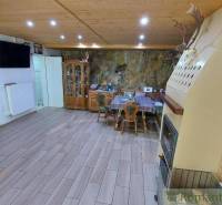 Spacious kitchen with a wooden ceiling, fireplace, and dining table in a family house.