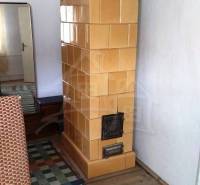 Tiled stove, wooden floor, mirror, carpet in a family house.
