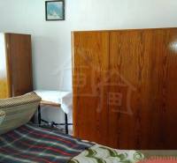 A room in a family house with antique wardrobes and a bed with a colorful blanket.