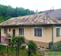 A family house in Fričovce with a sloped roof, garden, and surrounding forest.