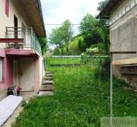 A family house in Fričovce with an unkempt garden, next to neglected facades and a staircase.