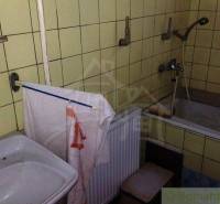 A bathroom in a family house with a sink, a bathtub, and yellow tiles.