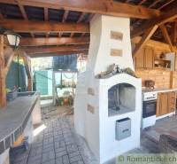 In the family house, there is an outdoor kitchen with an oven, wooden elements, and a stove.