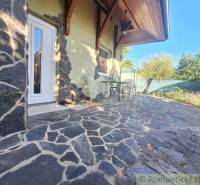 A family house in Komárno with a stone terrace, table, and chairs in the garden.