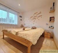 Bedroom in a family house with simple wooden furniture and decorative wall decoration.
