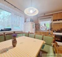 A kitchen in a family house with wooden furniture, a dining table, and an equipped kitchen unit.
