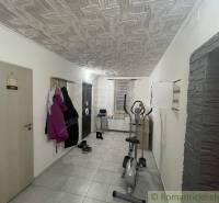 A corridor with tiles, an exercise machine, and a coat rack in a family house.