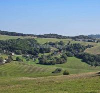 A hilly landscape with family houses in Malá Lehota, surrounded by meadows and forests.
