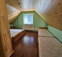 Attic room in a family house with beds and a wooden decor floor.