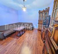 Living room in a family house, wooden furniture, corner sofa, light blue walls.