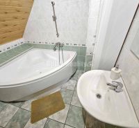 A bathroom with a corner bathtub and a sink in a family house.