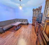 Living room of a family house with a wooden decor floor, a sofa, and dark wood furniture.