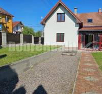 A family house in Malá Lehota with a landscaped garden, walkway, and fencing.