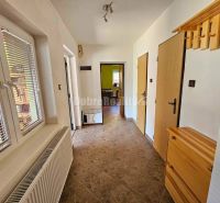 A hallway in a family house with tiles, wooden furniture, windows with blinds.