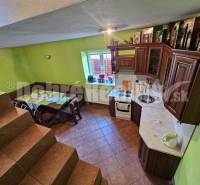 A kitchen with a wooden cabinet and a dining area, stairs in a family house.