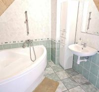 Bathroom in a family house with a corner bathtub, ceramic tiles, white sink.