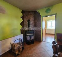 Living room in a family house with a fireplace, tiled stove, and wooden floor decor.