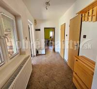Hallway in a family house with tiles, a coat rack, and a window with blinds.